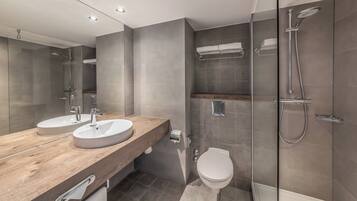 A modern bathroom with two sinks, a toilet, and a walk-in shower.