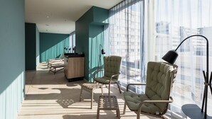 Un área de descanso moderna con un sofá, sillones, una mesita y un escritorio con lámpara.