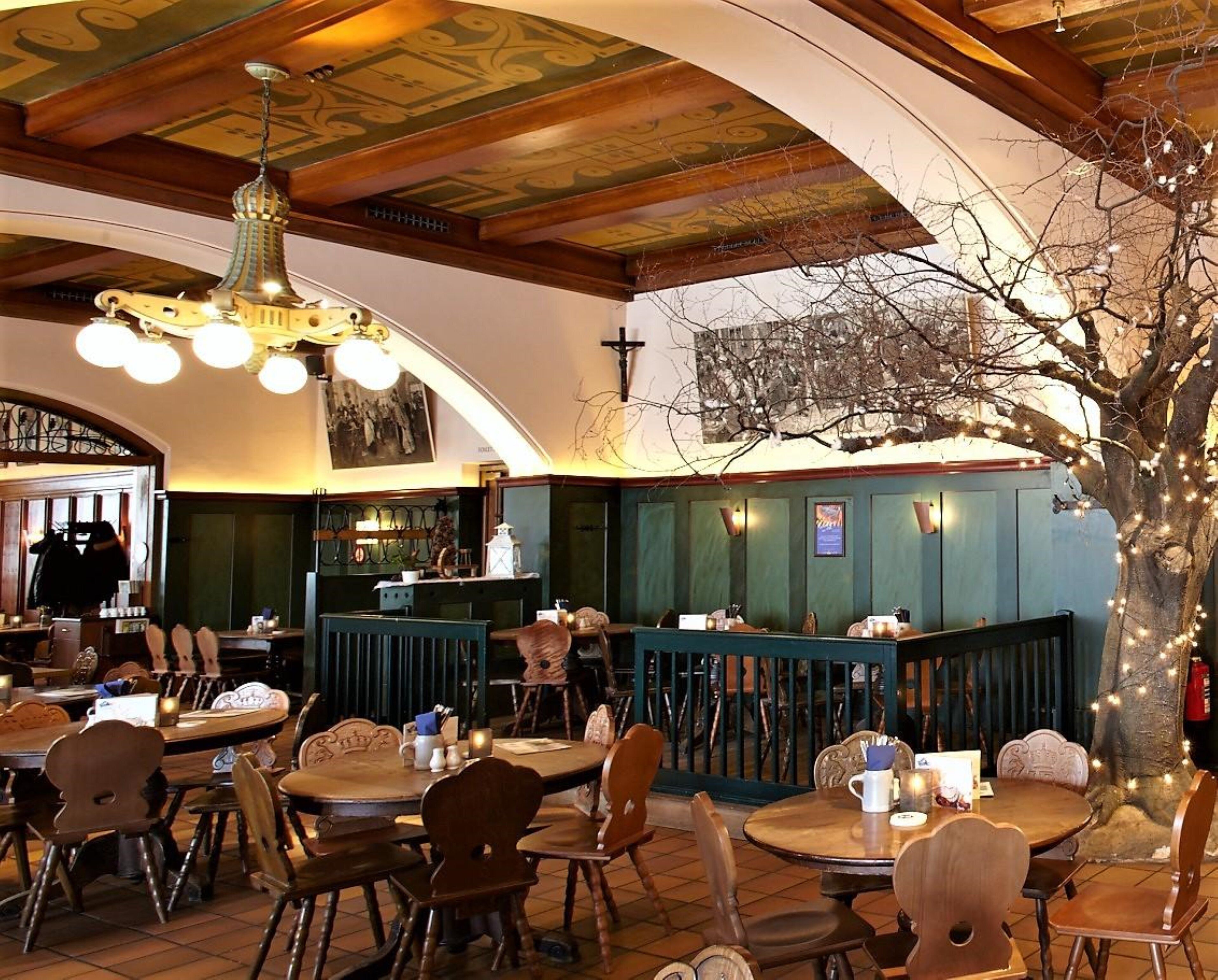 Ein Restaurant mit Holztischen, einer Bar und einem Wandgemälde.