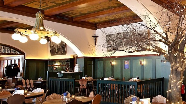 A restaurant with wooden furniture, a bar area, and a mural on the wall.