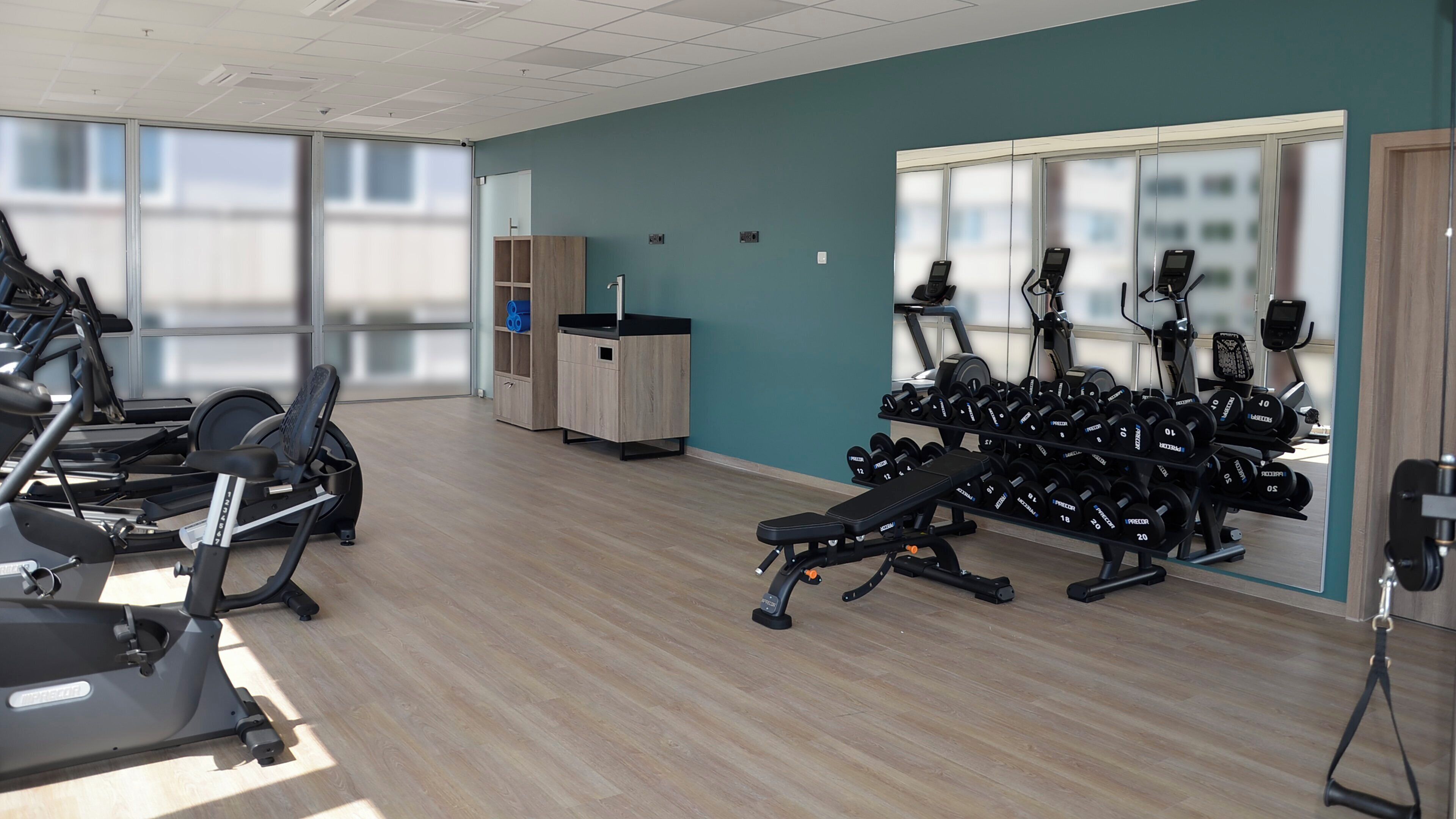 Un gimnasio con máquinas de cardio, bancos de pesas y mancuernas.