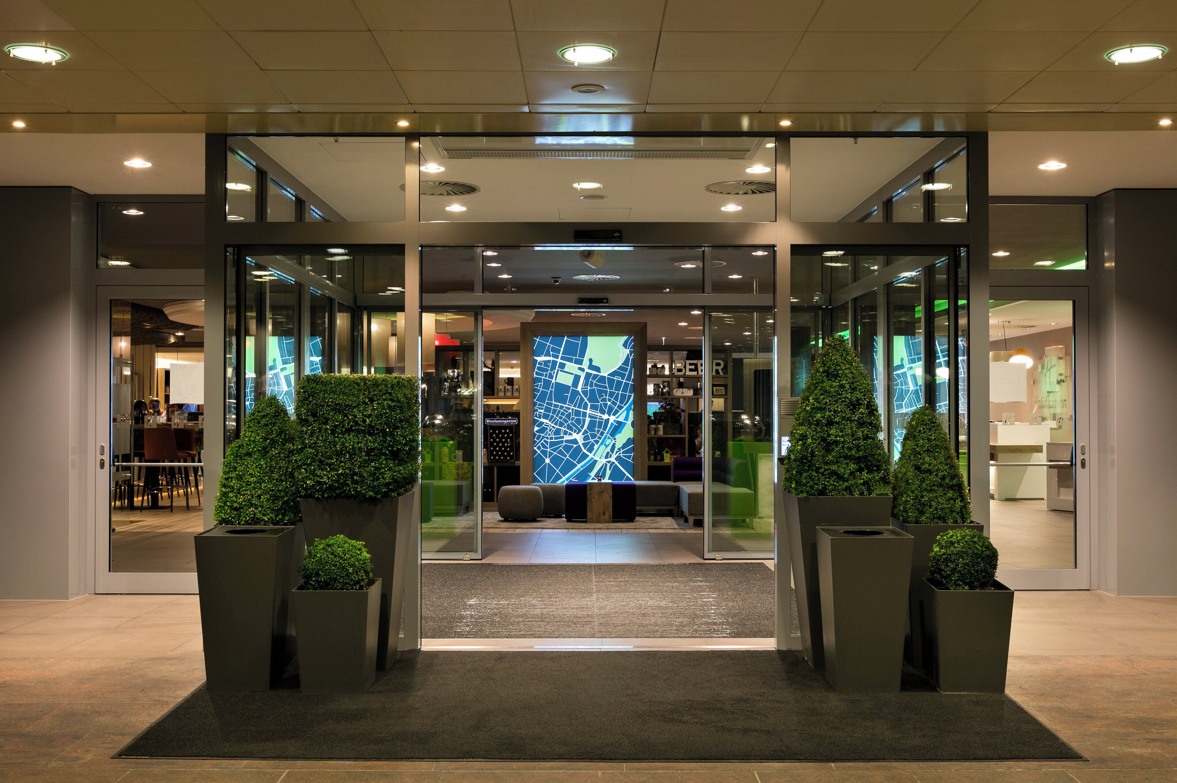 Ein Hotel Eingang mit Glastüren, einer Rezeption und einer Sitzecke mit einer Kartenanzeige.