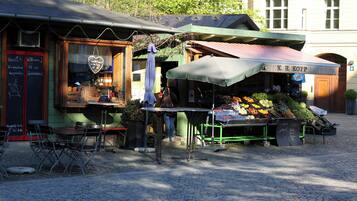 Un étal de marché installé au bord de la rue, où sont exposés des produits frais, et sur lequel on peut lire l’inscription « K.R. KOPP ».
