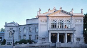 A classical building with a prominent entrance and statues on the roof. - Holiday Inn Munich - City Centre by IHG (Munich)