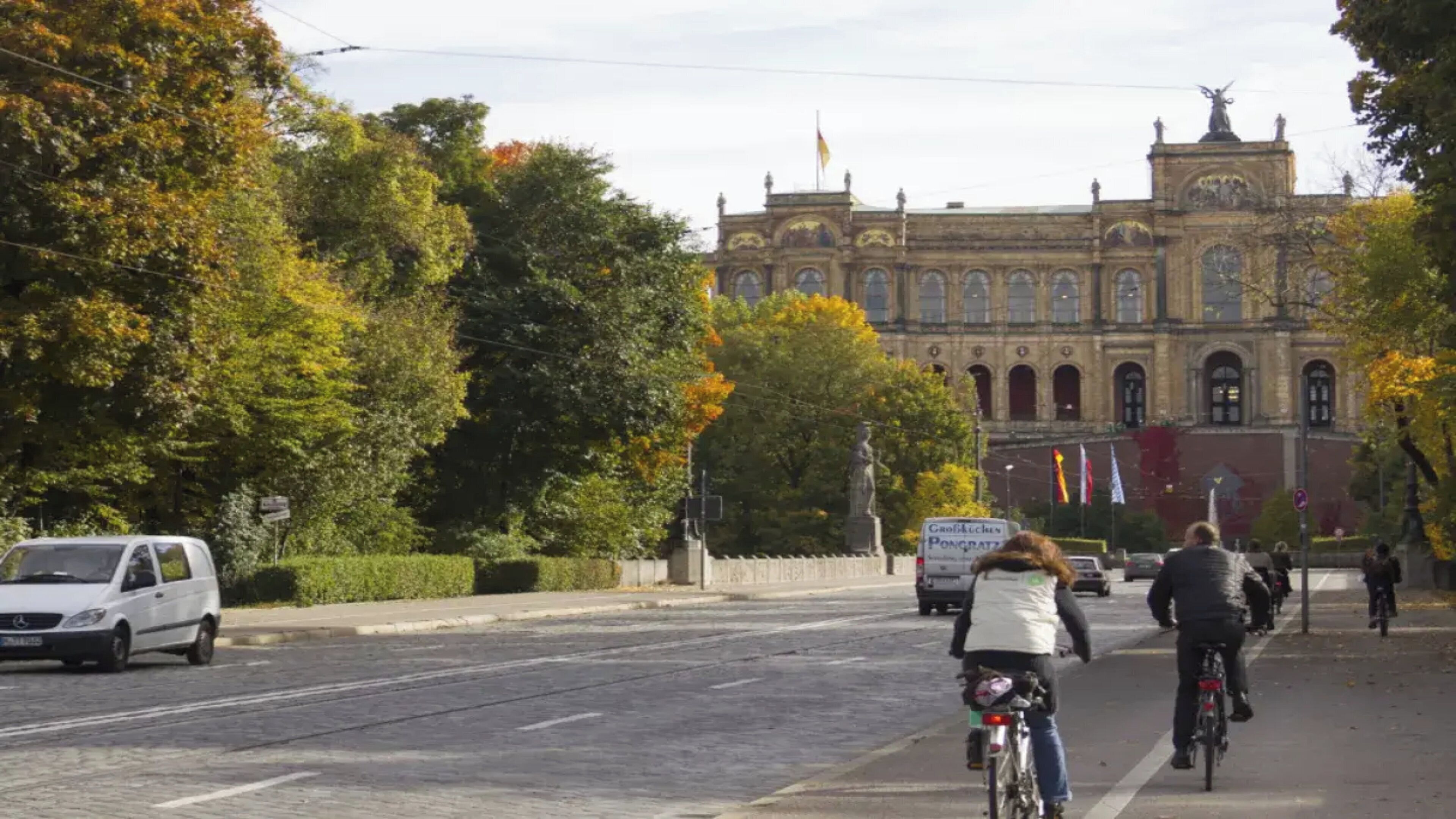 Una calle con tranvía, un edificio de arquitectura clásica y ciclistas.