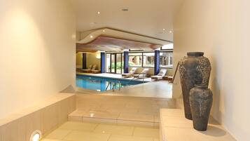 Alberca techada, sombrillas en la alberca y camastros