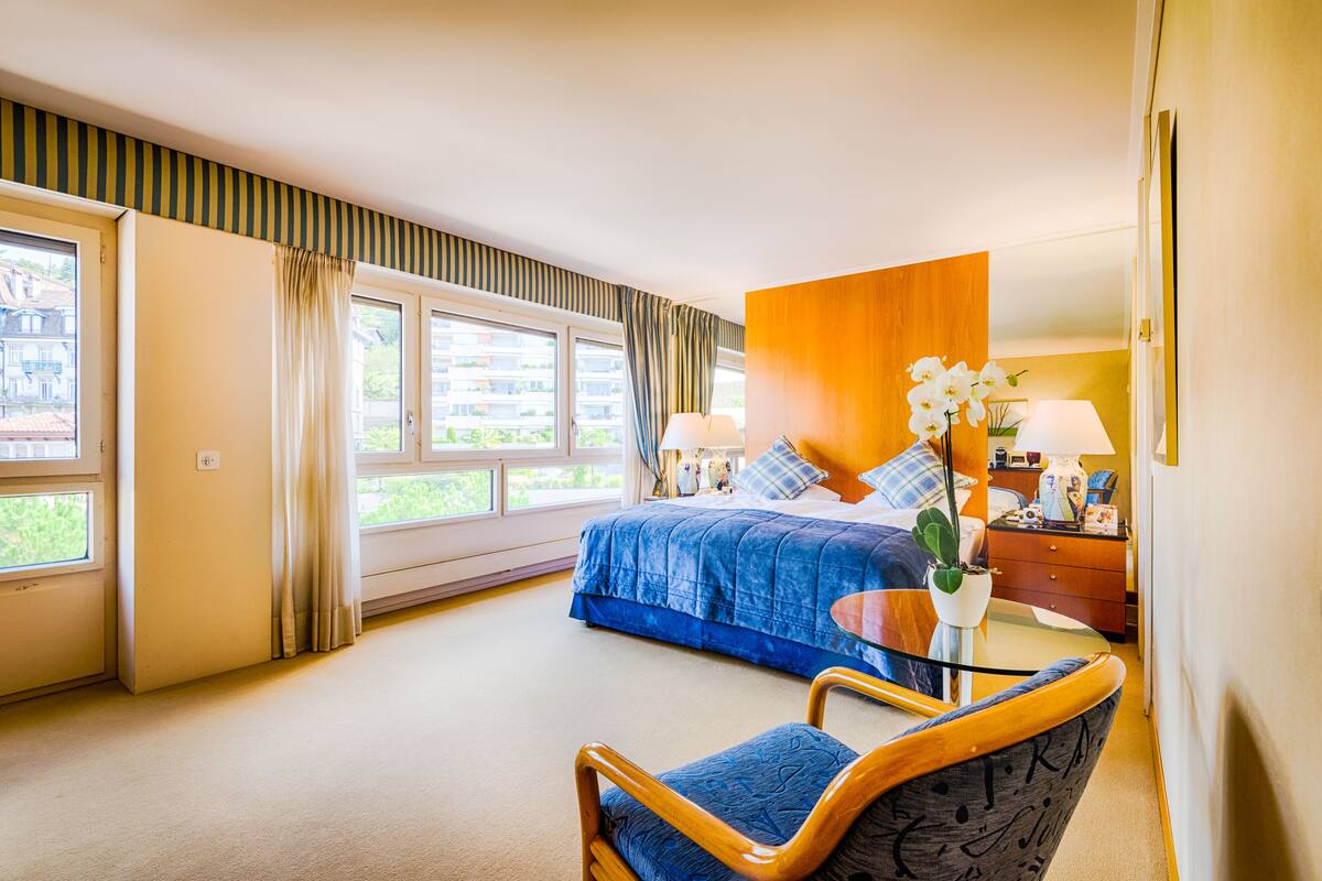 Una habitación de hotel con cama, una silla, una mesita y una ventana con cortinas.