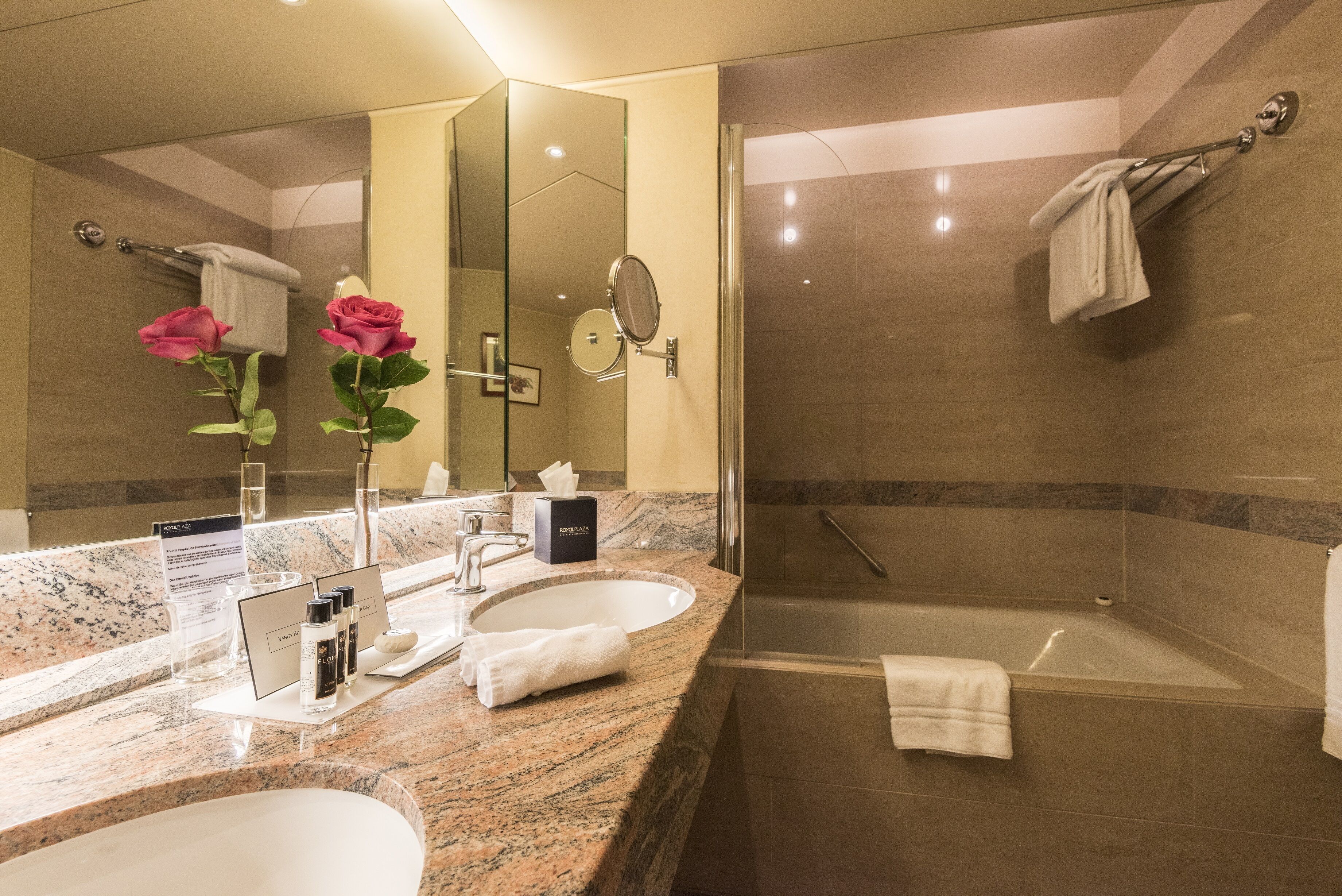 A modern bathroom with two sinks, a large mirror, a glass shower enclosure, and a bathtub.
