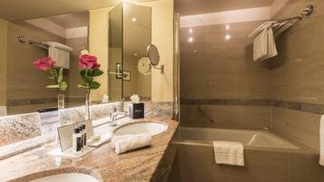A modern bathroom with two sinks, a large mirror, a glass shower enclosure, and a bathtub.