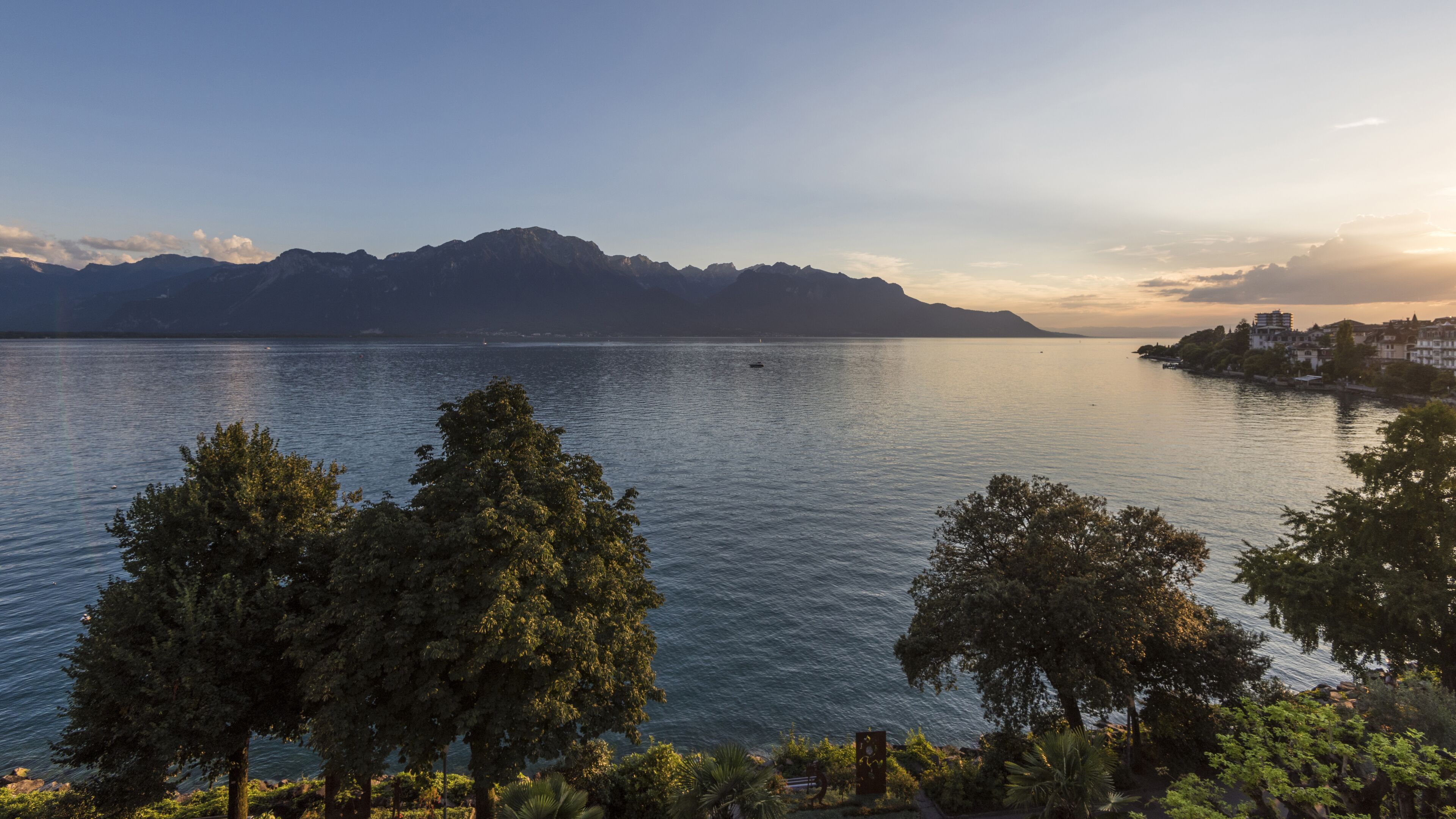 A lake with mountains in the background, surrounded by trees.