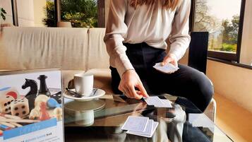 A person playing a card game at a table with a coffee cup and a board game set.