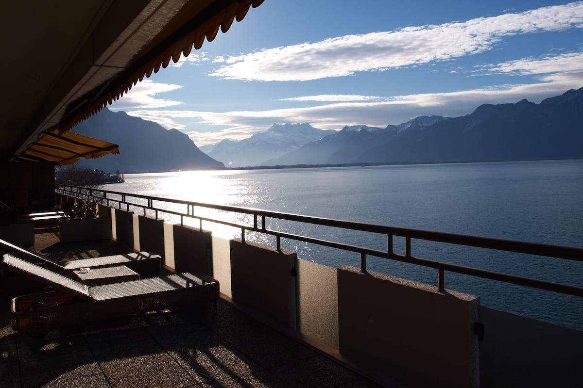 Una terraza con vistas a un lago y montañas.