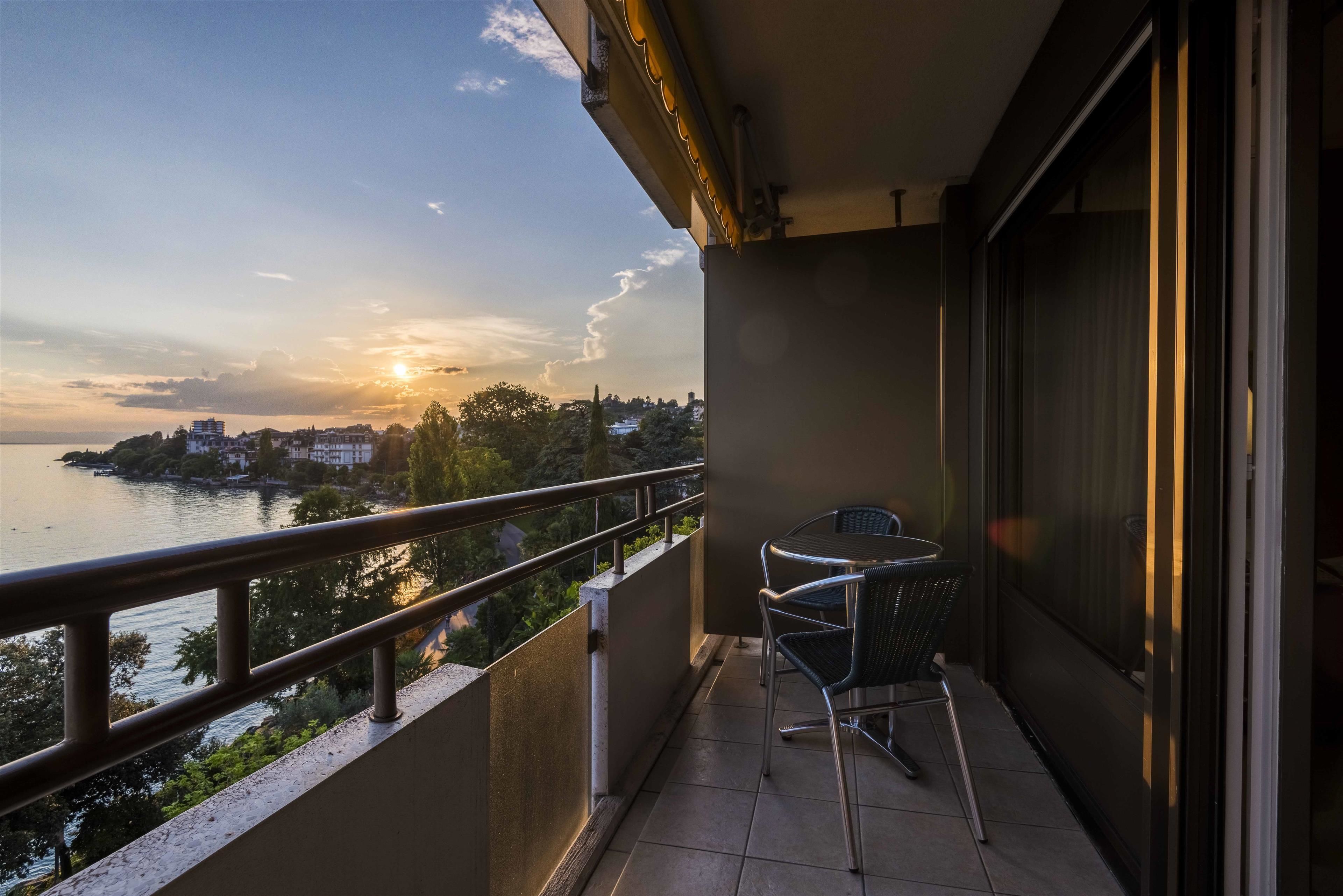 A balcony with a view of a body of water and buildings across the horizon.