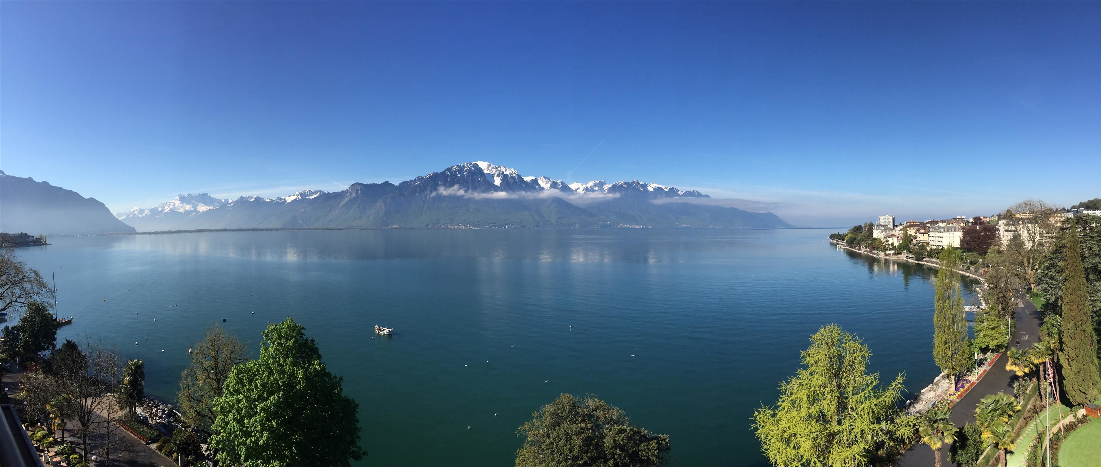A lake with mountains in the background, a clear sky, and a view of a town on the right.