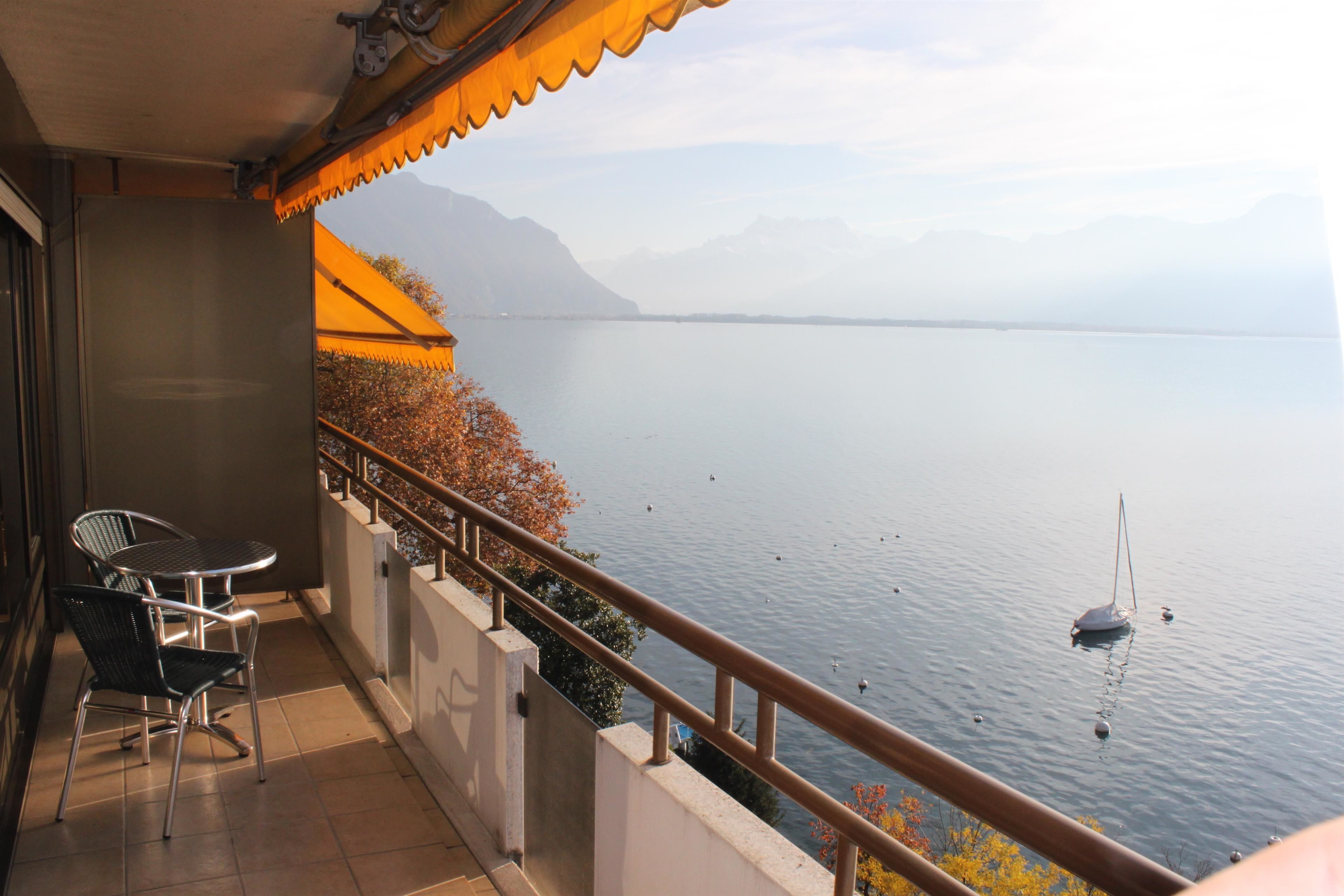 Un balcon offrant une vue sur un lac paisible et des montagnes au loin.