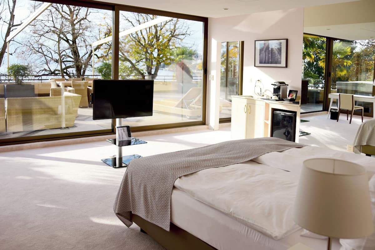 Una habitación de hotel moderna con un ventanal grande, una cama, un escritorio y un televisor.