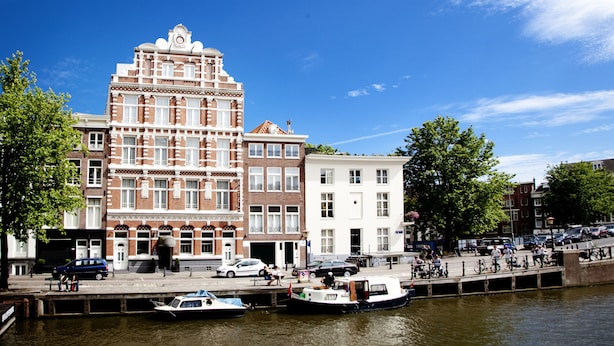 A historic hotel with a classic facade, a canal view, and a pedestrian walkway along the water. - Hotel Nes Amsterdam (Amsterdam)