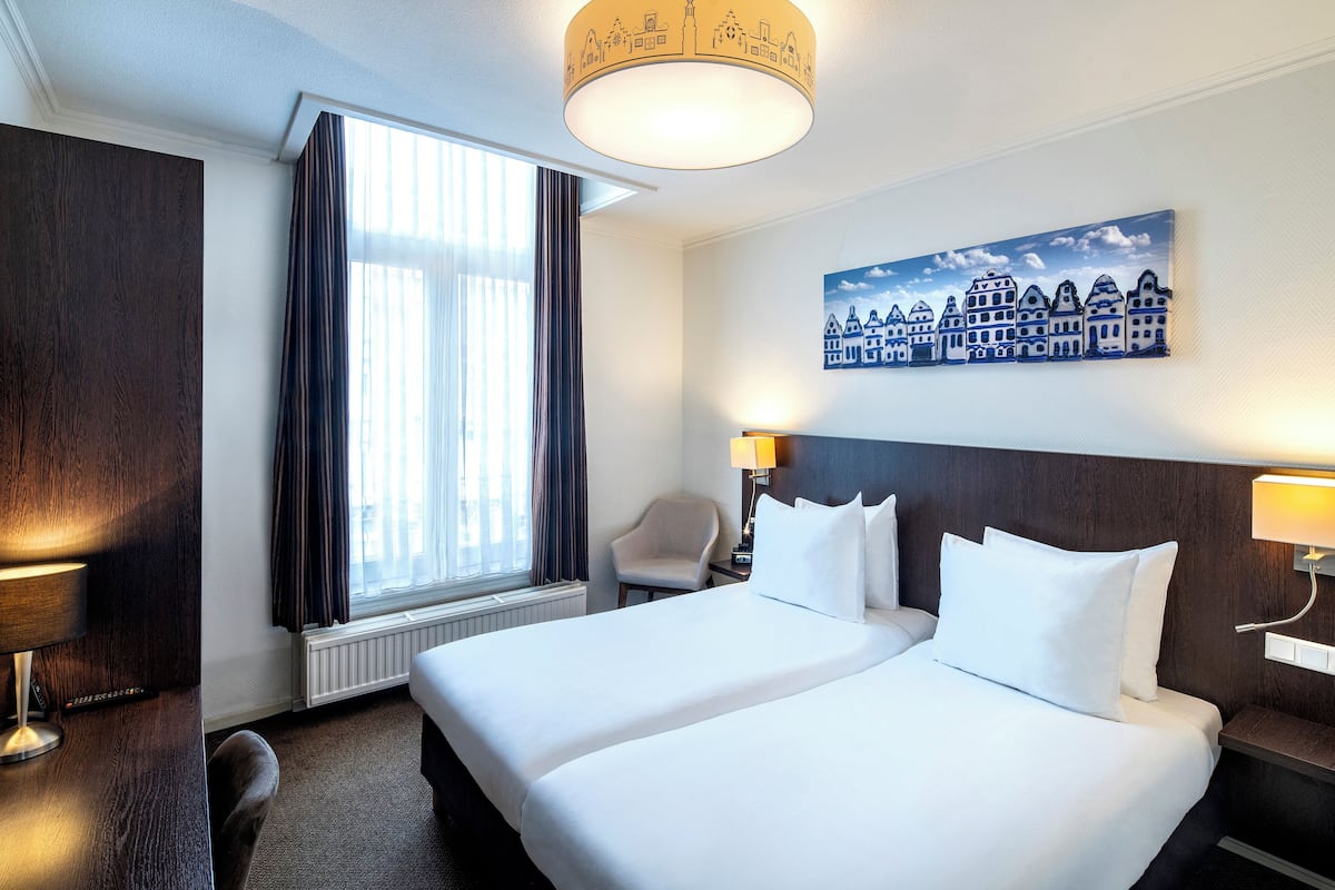 Habitación de hotel con una cama grande, una silla, un escritorio y una ventana con cortinas.