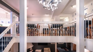 A spacious, multi-level interior with a staircase, a dining area, and a seating area with a chandelier. - Hotel Nes Amsterdam (Amsterdam)