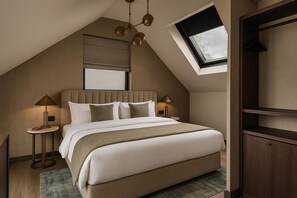 A bedroom with a sloped ceiling, a bed with white bedding, two bedside lamps, a window with a view, and a built-in shelving unit. - Hotel Satori Amsterdam, Tapestry Collection by Hilton (Amsterdam)