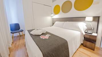 Ein ordentlich eingerichtetes Hotelzimmer mit Bett, Nachttisch, Lampe und einem Sessel.