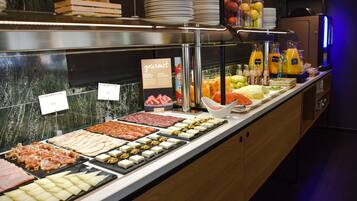 Een buffet met diverse gerechten, waaronder vleeswaren, kazen en fruit.