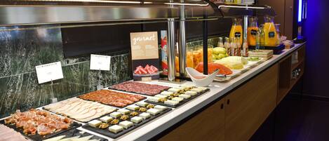Un bufé con diversas opciones de comida, incluyendo carnes, quesos y frutas.
