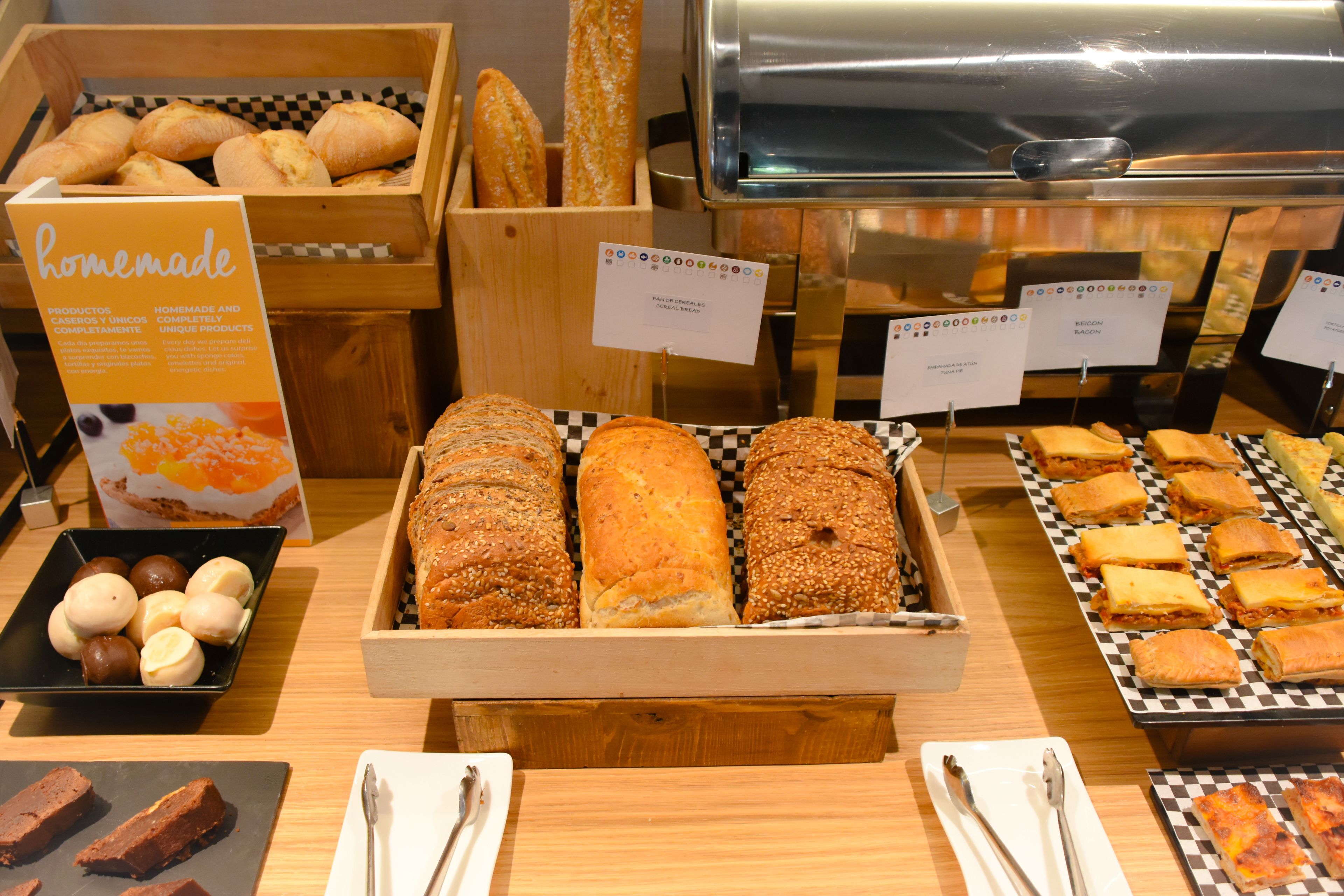 A bakery display with various breads and pastries, including a sign for homemade products.