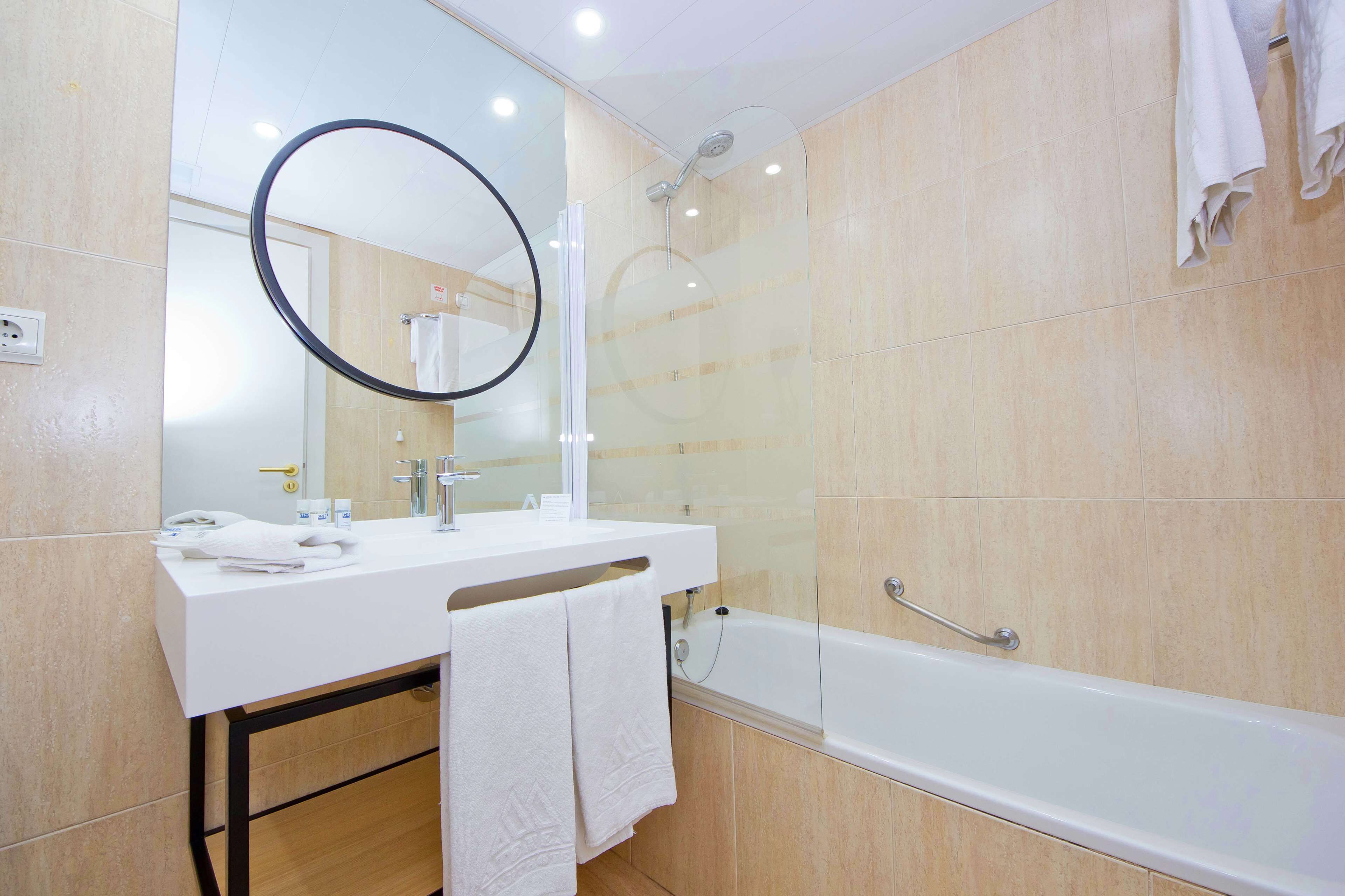 Une salle de bain moderne avec un lavabo blanc, un miroir et une baignoire.