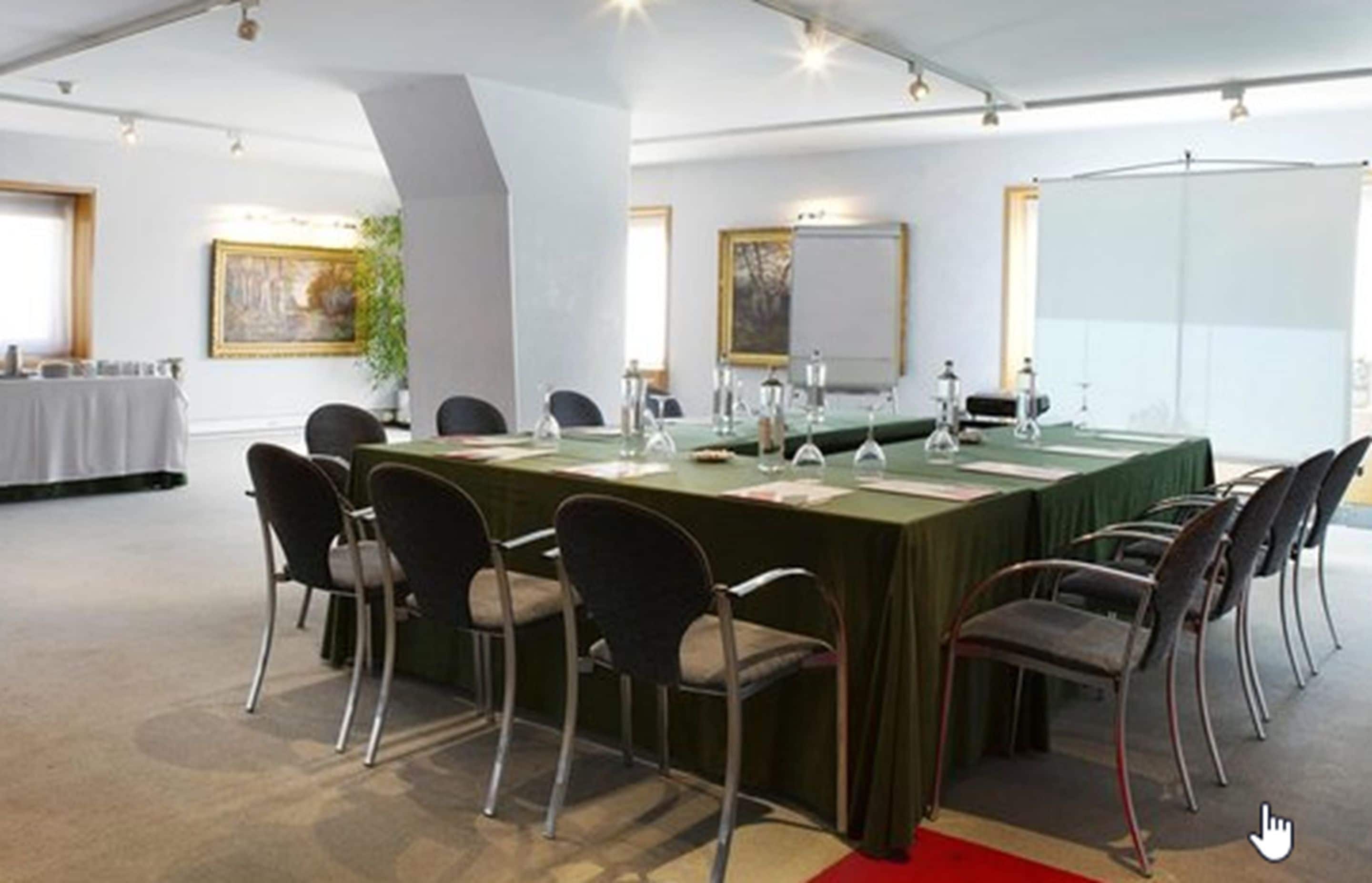 Un salón de conferencias con una larga mesa, sillas y una pantalla para proyector.