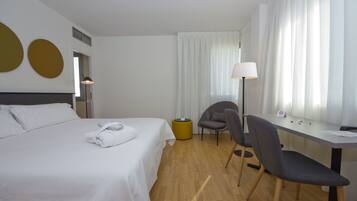 Une chambre d’hôtel avec un lit, un bureau, une chaise et une lampe.