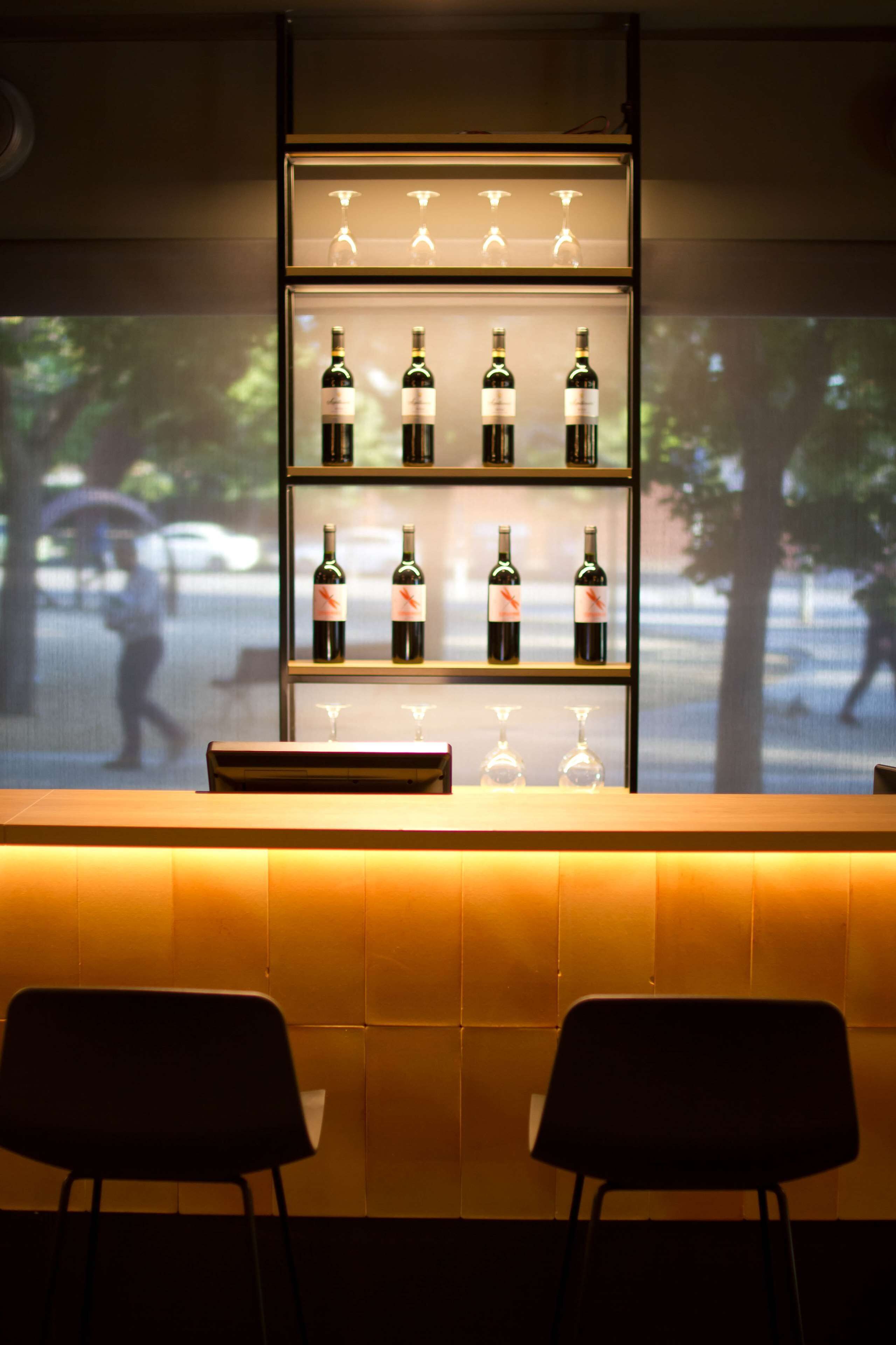 Zona de bar con una vitrina de vinos y dos sillas negras.