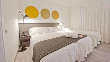 Una habitación de hotel con cama, mesitas de noche, lámpara y cortina.