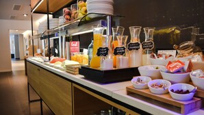 A buffet with various food items and beverages, including fruits, cheeses, and sauces, displayed on a counter with a modern design. - Aparthotel Atenea Valles (Granollers)