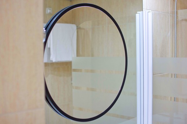 A bathroom with a glass shower enclosure and a mirror. - Aparthotel Atenea Valles (Granollers)