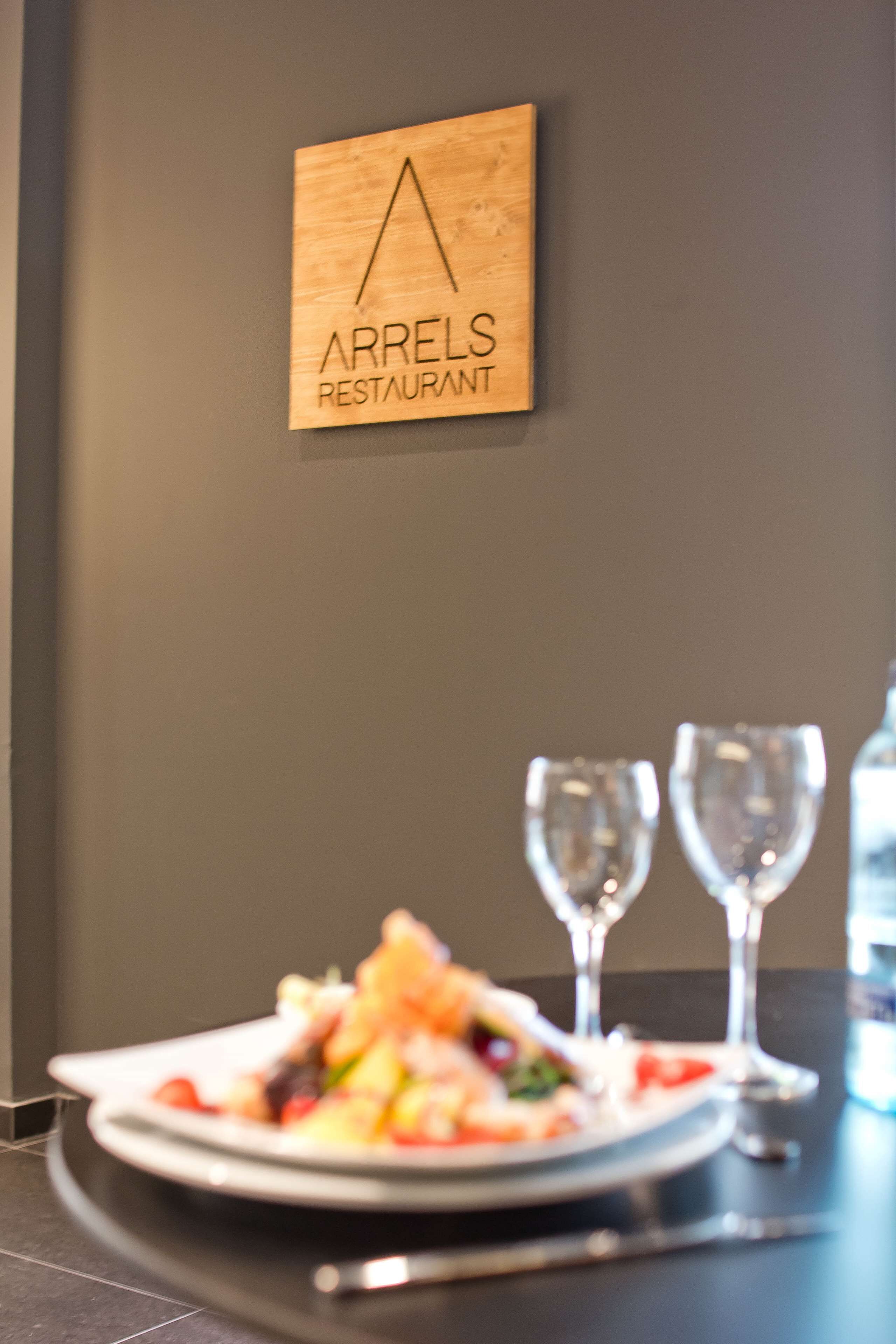 A restaurant sign, a plate of food, and two empty wine glasses on a table.