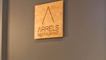 A restaurant sign, a plate of food, and two empty wine glasses on a table.
