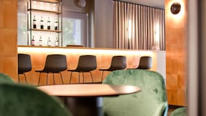 A bar area with a counter, several chairs, and a green upholstered sofa. - Aparthotel Atenea Valles (Granollers)