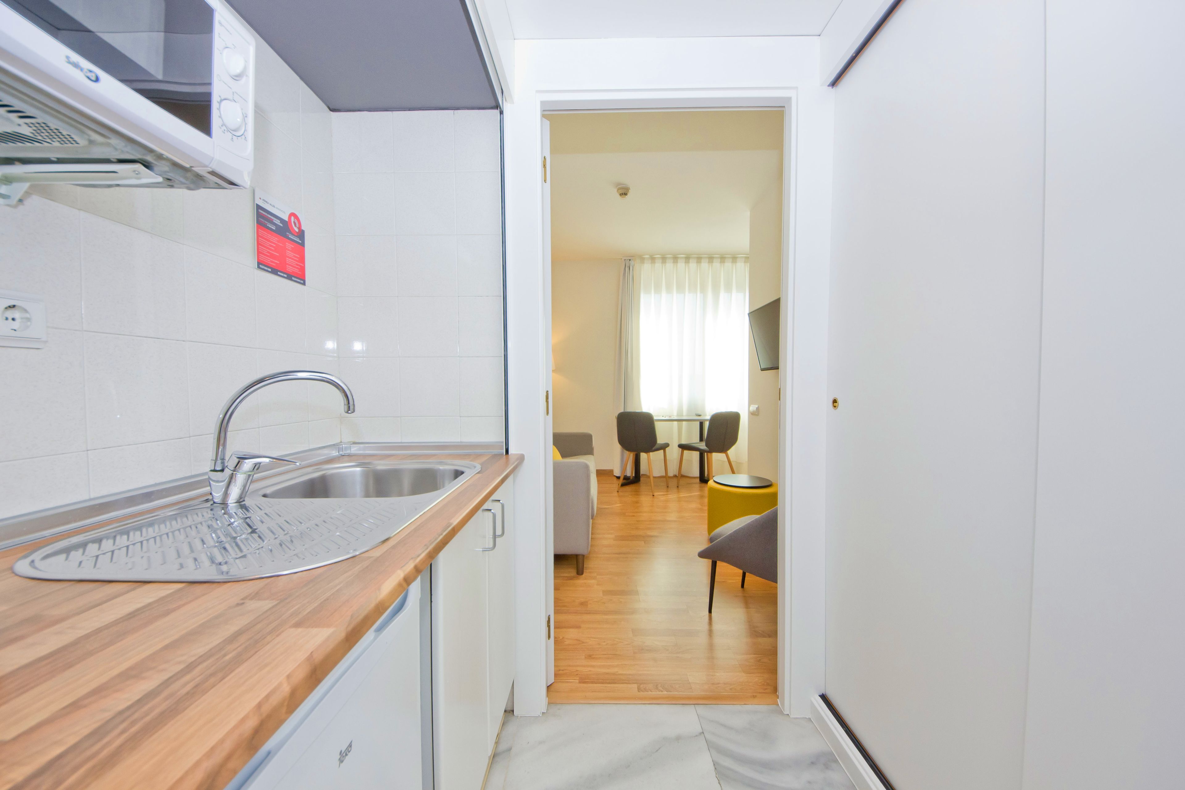 A compact kitchen with a modern sink, a microwave, and a small dining area with a table and chairs.