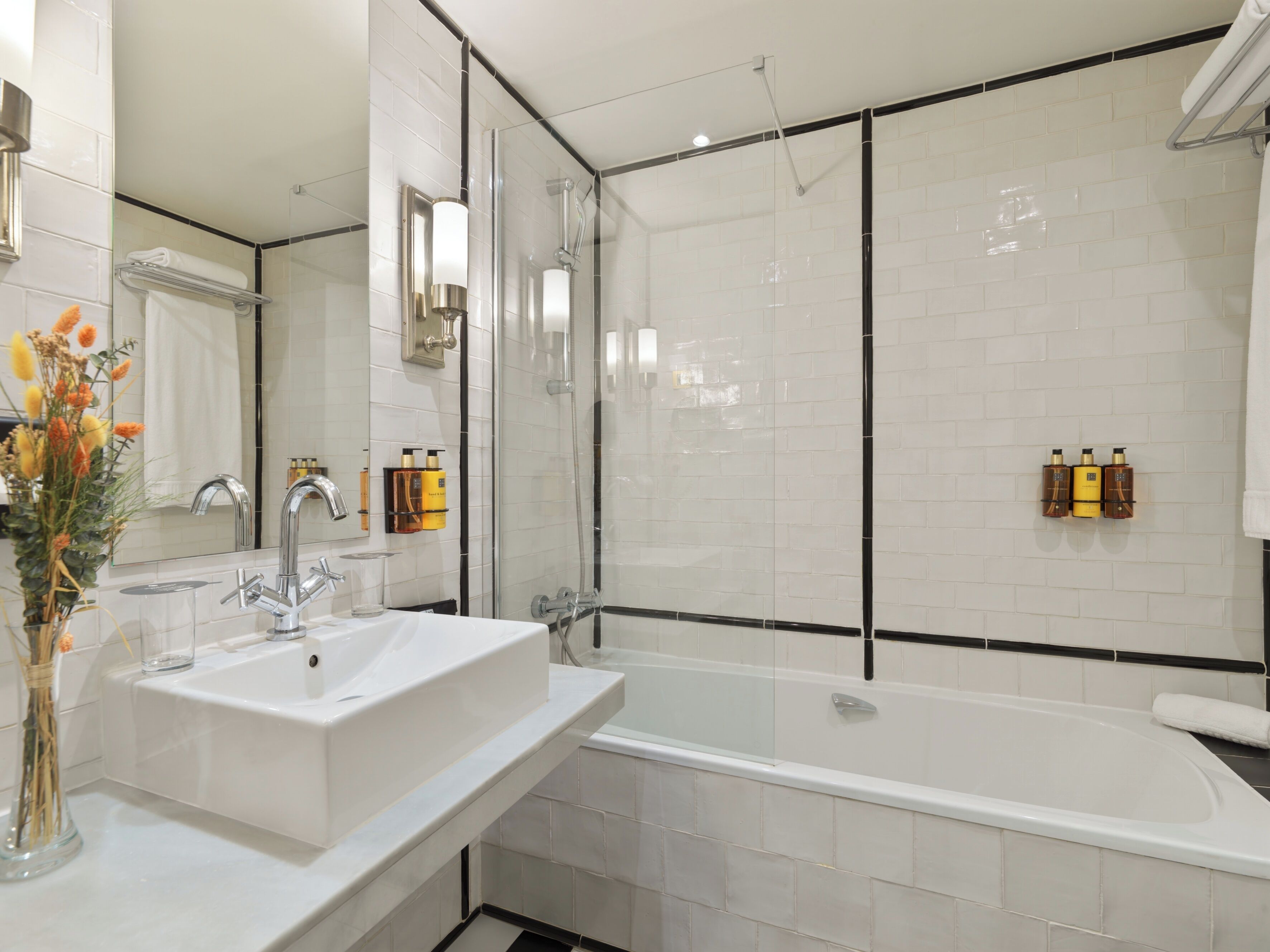 A modern bathroom with a white sink, a glass-enclosed shower, and a bathtub.