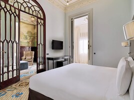 Camera d'albergo con un letto grande, una scrivania, una TV e uno specchio decorativo.