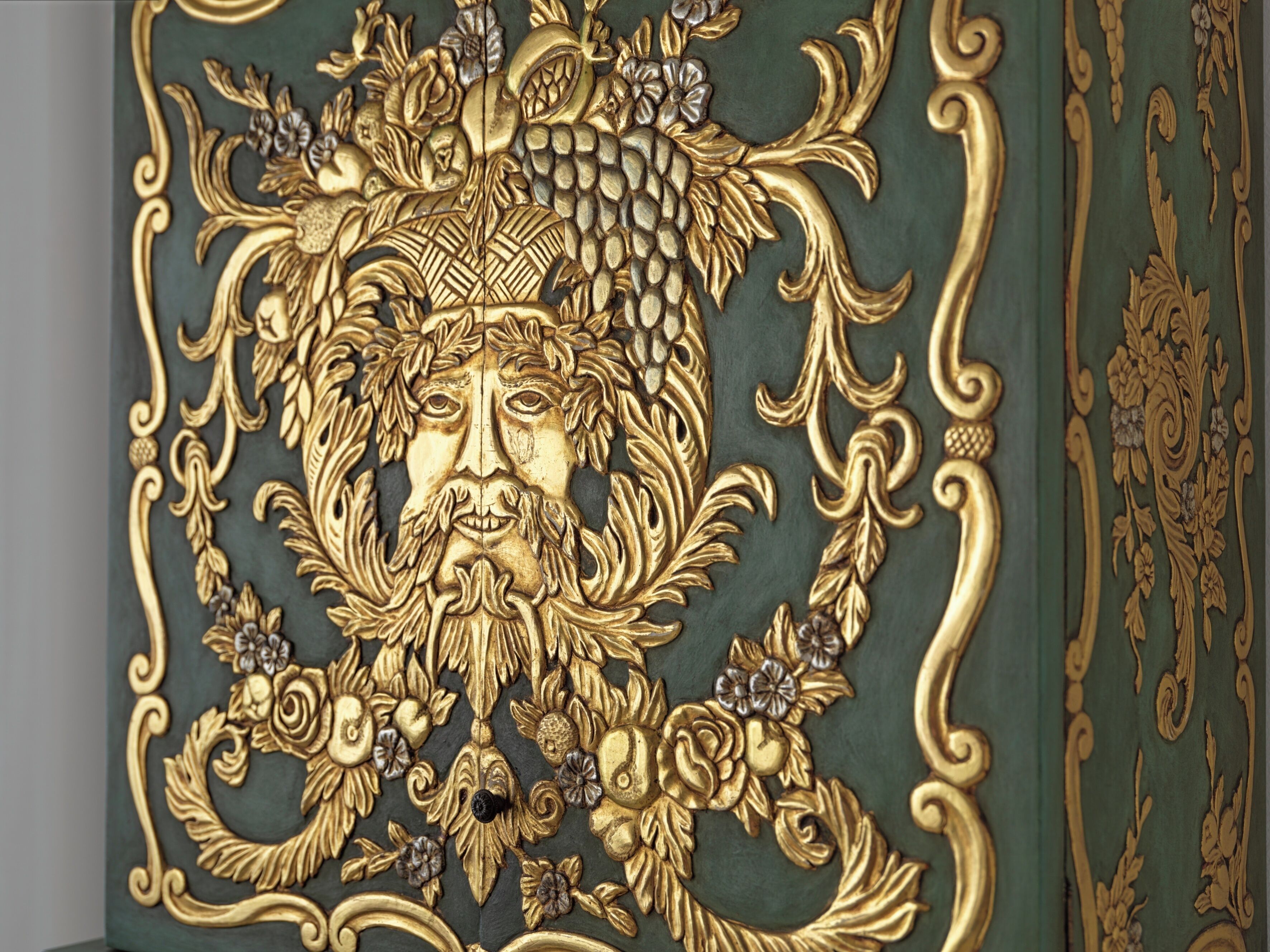 A detailed gold and green decorative panel with intricate floral and leaf patterns.