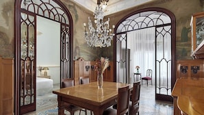 Una sala da pranzo con tavolo in legno, sedie, un lampadario e un grande specchio.