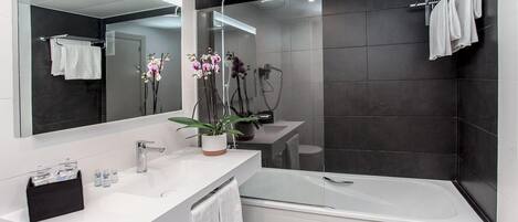A modern bathroom with a large mirror, white sink, and a glass-enclosed shower.