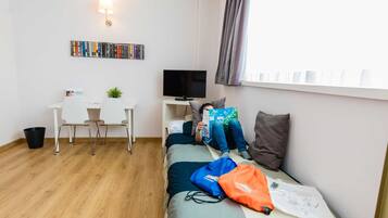 A modern room with a bed, a desk, a TV, and a bookshelf.