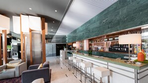 A modern bar area with a marble countertop, bar stools, and a variety of bottles and glasses. - Aparthotel Atenea Barcelona (Barcelona)