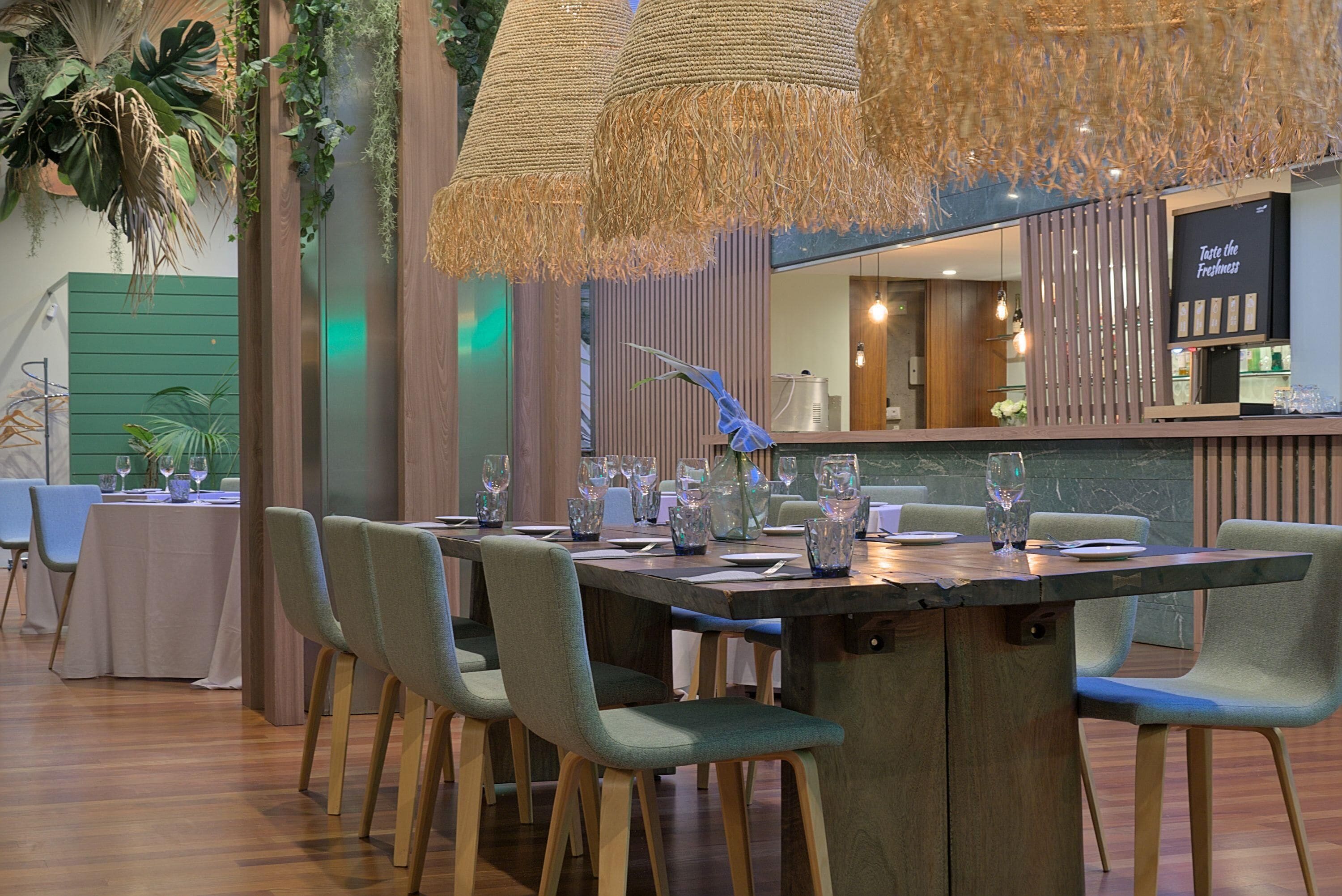 A dining area with a long table set for six, surrounded by chairs, and a bar area with a counter and stools.