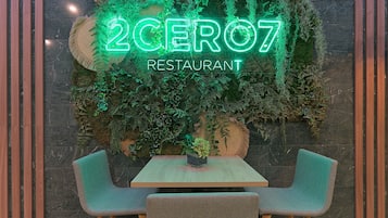 Interior de un restaurante con un letrero de neón, una mesa de madera y dos sillas.