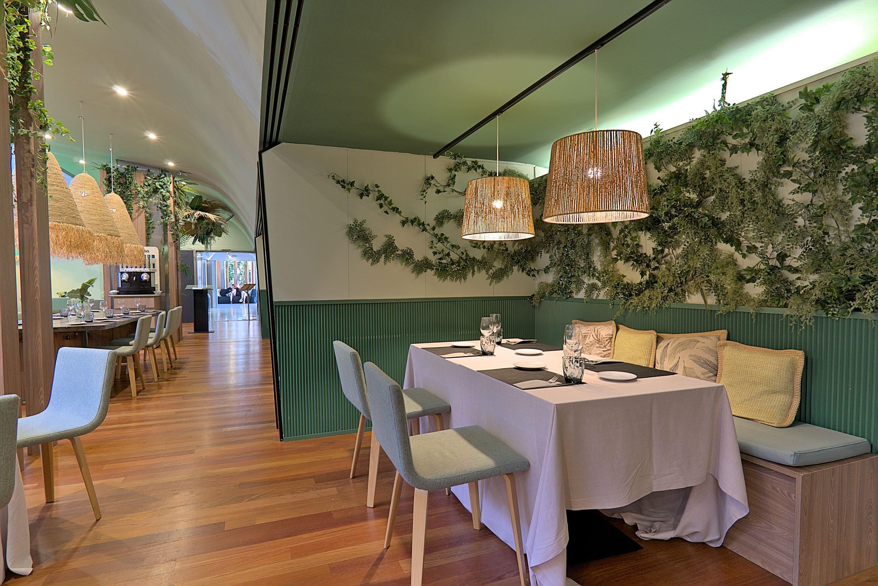 Een restaurant met een lange tafel gedekt voor het diner, stoelen en een bank met kussens.
