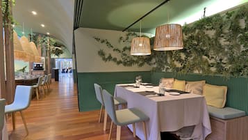 Een restaurant met een lange tafel gedekt voor het diner, stoelen en een bank met kussens.